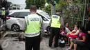 Polisi berjaga didekat mobil yang menabrak separator busway matraman arah kampung melayu, Jakarta, Sabtu (25/2). (Liputan6.com/Faizal Fanani)