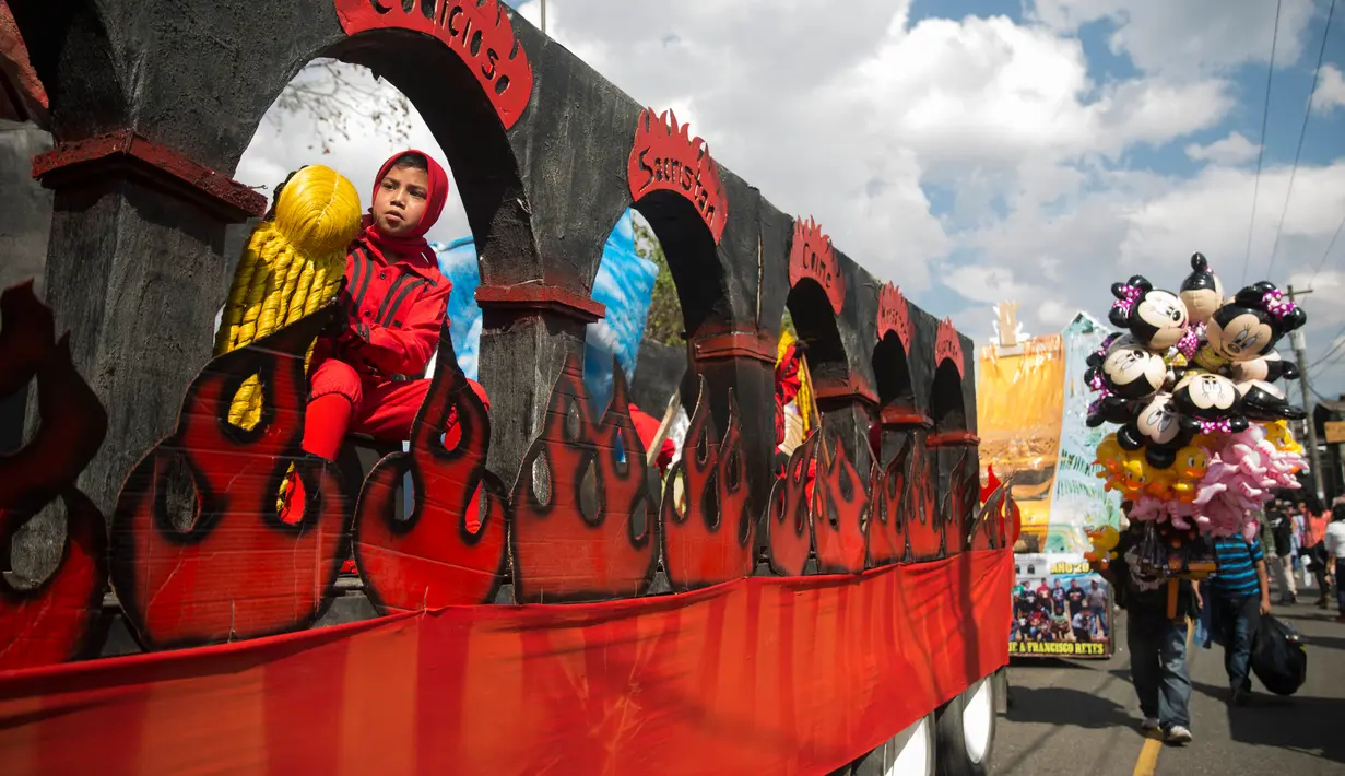 Seorang anak duduk di mobil hias mengenakan kostum saat mengikuti parade perayaan Virgin of the Immaculate Conception di Ciudad Vieja, Guatemala (7/12). Parade ini digelar setiap tahun pada tanggal 8 Desember. (AP Photo/Luis Soto)