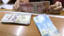 Petugas menunjukkan mata uang rupiah dan dolar di Jakarta, Senin (9/11/2020). Menjelang siang, rupiah terus menguat ke level 14.145 per dolar AS. (Liputan6.com/Angga Yuniar)