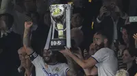 Bek Real Madrid, Marcelo (kiri) dan Karim Benzema mengangkat trofi untuk merayakan gelar La Liga Spanyol usai pertandingan melawan Espanyol di stadion Santiago Bernabeu di Madrid, Sabtu (30/4/2022). (AP Photo/Bernat Armangue)