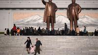 Sebuah keluarga berjalan menuruni tangga setelah memberikan penghormatan di depan dua patung pemimpin Korea Utara sebelumnya (AFP)