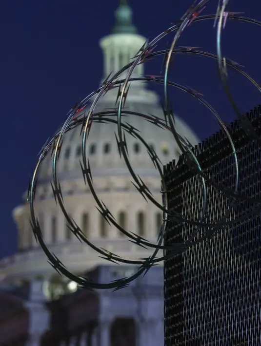 Pagar anti huru hara dan kawat berduri memperkuat zona keamanan di Capitol Hill, Washington, sebelum pelantikan Presiden terpilih Joe Biden, Selasa (19/1/2021). Pelantikan Biden berlangsung di tengah ancaman kekerasan dari pendukung Donald Trump dan pandemi Covid-19. (AP Photo/J. Scott Applewhite)