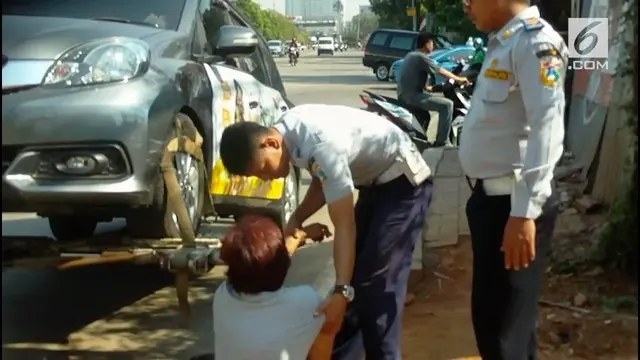 Seorang wanita berteriak histeris pada petugas agar kendaraannya tak diderek. Namun petugas tak bergeming dan menjalankan tugas.