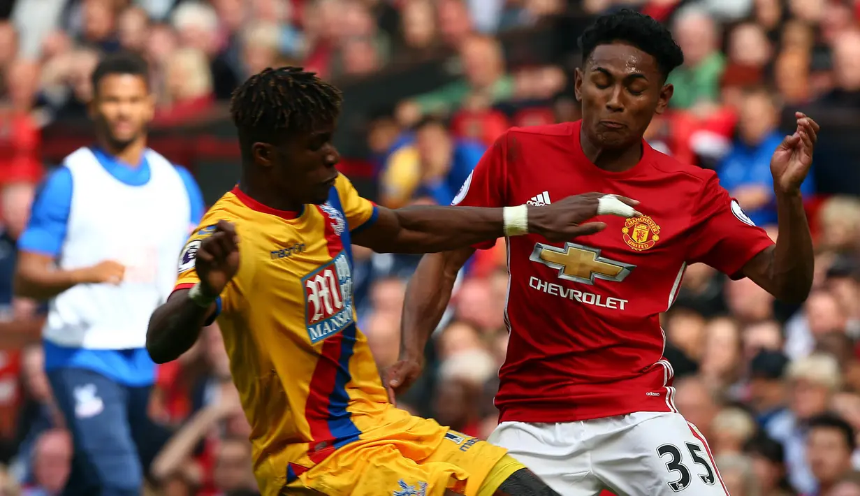 Striker Crystal Palace, Wilfried Zaha, beradu badan dengan bek Manchester United, Demitri Mitchell, pada laga Premier League di Stadion Old Trafford, Inggris, Minggu (21/5/2017). MU menang 2-0 atas Palace. (EPA/Tim Keeton)