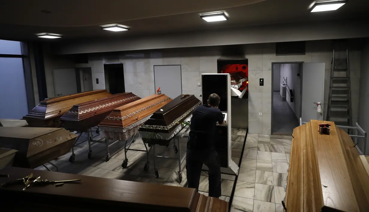 Seorang pekerja memindahkan peti jenazah untuk dibakar di sebuah krematorium di Ostrava, Republik Ceko pada 7 Januari 2021. Krematorium terbesar di Ceko dan satu-satunya di wilayah itu telah kewalahan dalam mengkremasi jasad-jasad korban COVID-19 yang terus bertambah. (AP Photo/Petr David Josek)