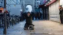 Seorang anggota komunitas Kurdi berlutut di tanah saat dia ditahan selama bentrokan dengan petugas polisi dekat TKP penembakan di Paris, Prancis, 23 Desember 2022. Pemerintah Prancis menduga penembakan di pusat budaya Kurdi ini bermotif rasial. (AP Photo/Lewis Joly)