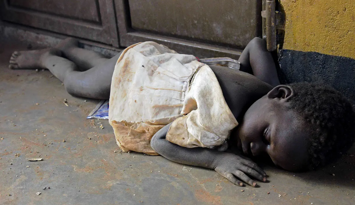 Seorang anak pengungsi dari Sudan Selatan tidur saat singgah di Pos Perbatasan Ngomoromo, Uganda, Senin (10/4). Sudan kini sedang mengalami bencana kelaparan, kekeringan dan perang saudara. (AFP PHOTO / ISAAC KASAMANI)