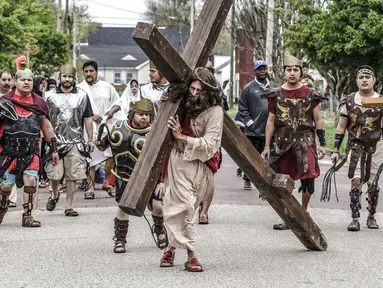 Anggota Gereja Katolik St. Joseph dan Paul berjalan menyusuri Seventh Street saat Live Way of the Cross atau pemeragaan kembali perjalanan Yesus menuju penyaliban-Nya pada peringatan Jumat Agung di Owensboro, Kentucky, Amerika Serikat, 15 April 2022. (Greg Eans/The Messenger-Inquirer via AP)