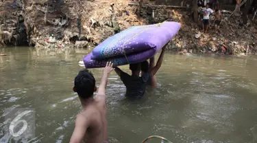 Sejumlah warga membawa kasur menyeberangi kali Ciliwung usai penggusuran di Kampung pulo, Jakarta, Jumat (21/8/2015). Penggusuran terkait rencana Pemprov DKI Jakarta yang akan melakukan normalisasi Kali Ciliwung. (Liputan6.com/Gempur Surya)