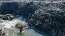 Warga memanfaatkan aliran Kali Pesanggrahan yang menyempit untuk mendulang benda-benda logam di kawasan Pasir Putih, Depok, Jawa Barat, Senin (27/4/2026), setelah longsoran sampah dari Tempat Pembuangan Akhir (TPA) Cipayung menutup sebagian badan sungai. (merdeka.com/Arie Basuki)