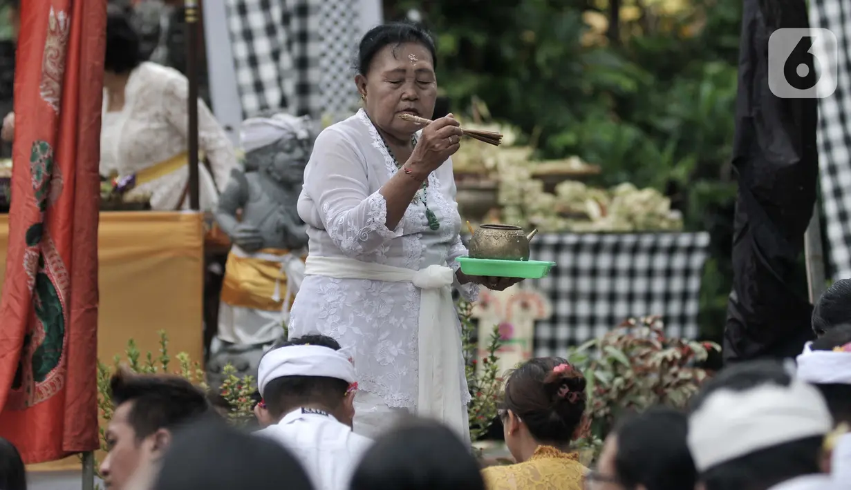 Pemuka agama Hindu memercikkan air suci saat persembahyangan Hari Raya Galungan di Pura Aditya Jaya, Rawamangun, Jakarta, Rabu (19/2/2020). Hari Raya Galungan yang merupakan hari kemenangan kebenaran (Dharma) atas kejahatan (Adharma) itu dirayakan setiap 210 hari sekali. (merdeka.com/Iqbal Nugroho)