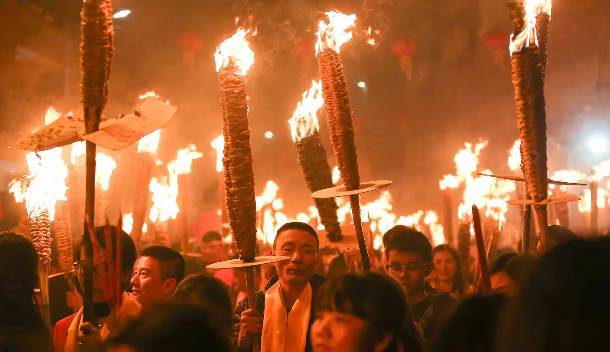 Warga berdoa sambil memegang obor saat mengikuti parade pada sebuah festival obor di Jinjiang di provinsi Fujian, China timur (24/2). Ratusan warga China mengikuti parade obor untuk keberhasilan di tahun yang baru. (AFP Photo)