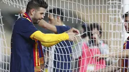 Bek Barcelona, Gerard Pique memotong sebagian jala gawang saat mereka merayakan kemenangan atas Athletic Bilbao pada final Copa del Rey Spanyol 2021 di stadion La Cartuja di Seville, Spanyol, Minggu (18/4/2021). Barcelona menang atas Athletic Bilbao 4-0. (AP Photo / Angel Fernandez)