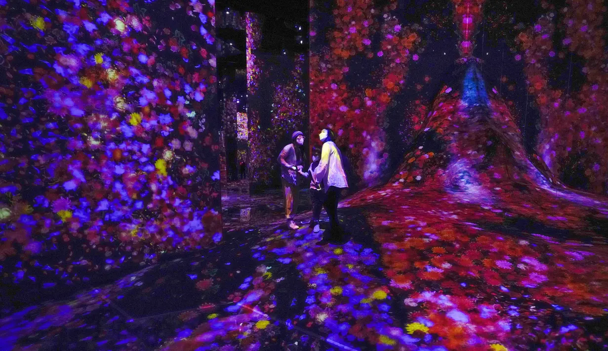 Anggota keluarga menikmati instalasi digital yang menampilkan proyeksi bunga bertajuk "Hutan Bunga dan Manusia: Hilang, Tenggelam, dan Terlahir Kembali" di museum "teamLab Massless" yang baru dibuka di Beijing, China, Senin (26/12/2022). Berbasis di Tokyo teamLab membuat museum seni digital yang memamerkan berbagai karya seni interaktif di dalam pusat perbelanjaan di ibu kota Beijing. (AP Photo/Andy Wong)
