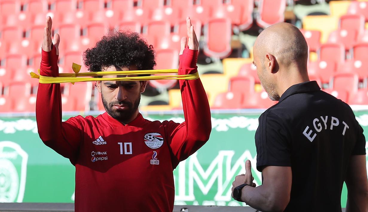 Pemain timnas Mesir Mohamed Salah dibantu tim kesehatan melatih bahunya yang cedera saat pelatihan di stadion Akhmat Arena di Grozny (12/6). Timnas Mesir berada di grup bersama Uruguay, Arab Saudi dan Rusia. (AFP Photo/Karim Jaafar)