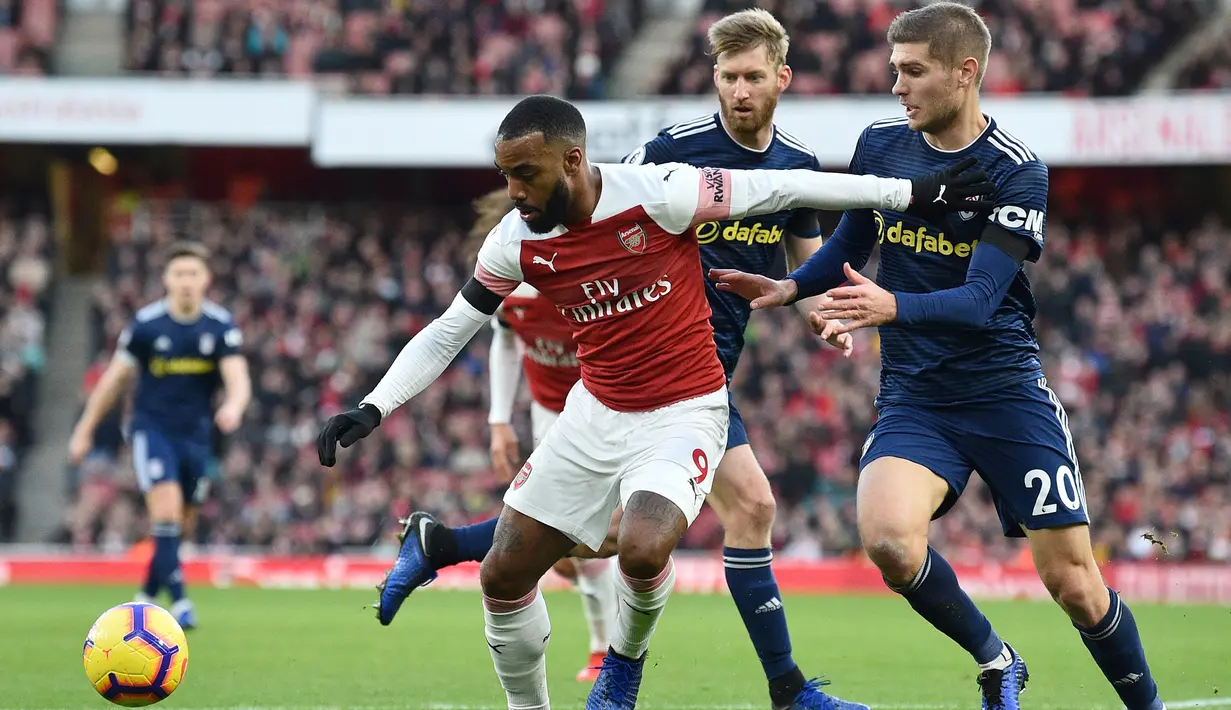 Striker Arsenal, Alexandre Lacazette, berusaha melewati bek Fulham, Maxime Le Marchand, pada laga Premier League di Stadion Emirates, London, Selasa (1/1). Arsenal menang 5-1 atas Fulham. (AFP/Glyn Kirk)