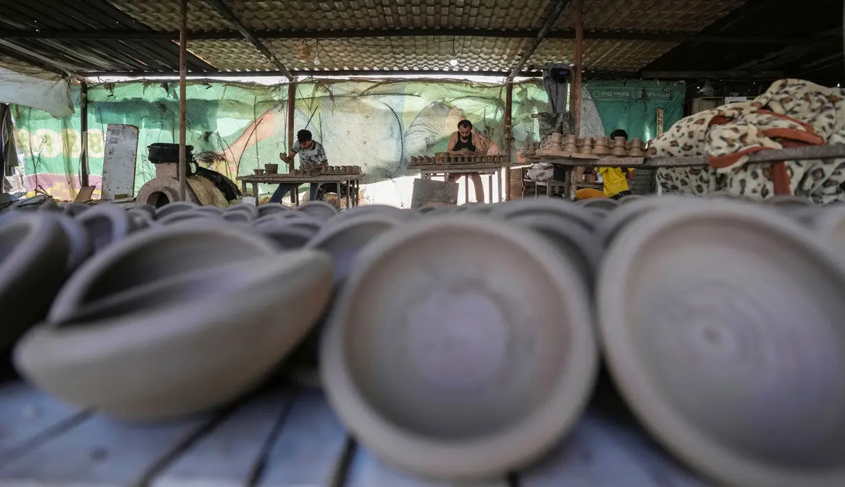 Sejumlah pria membentuk bejana tanah liat di salah satu bengkel tembikar tertua di Beit Lahia, Jalur Gaza, 15 Agustus 2022. (AP Photo/Hatem Moussa)