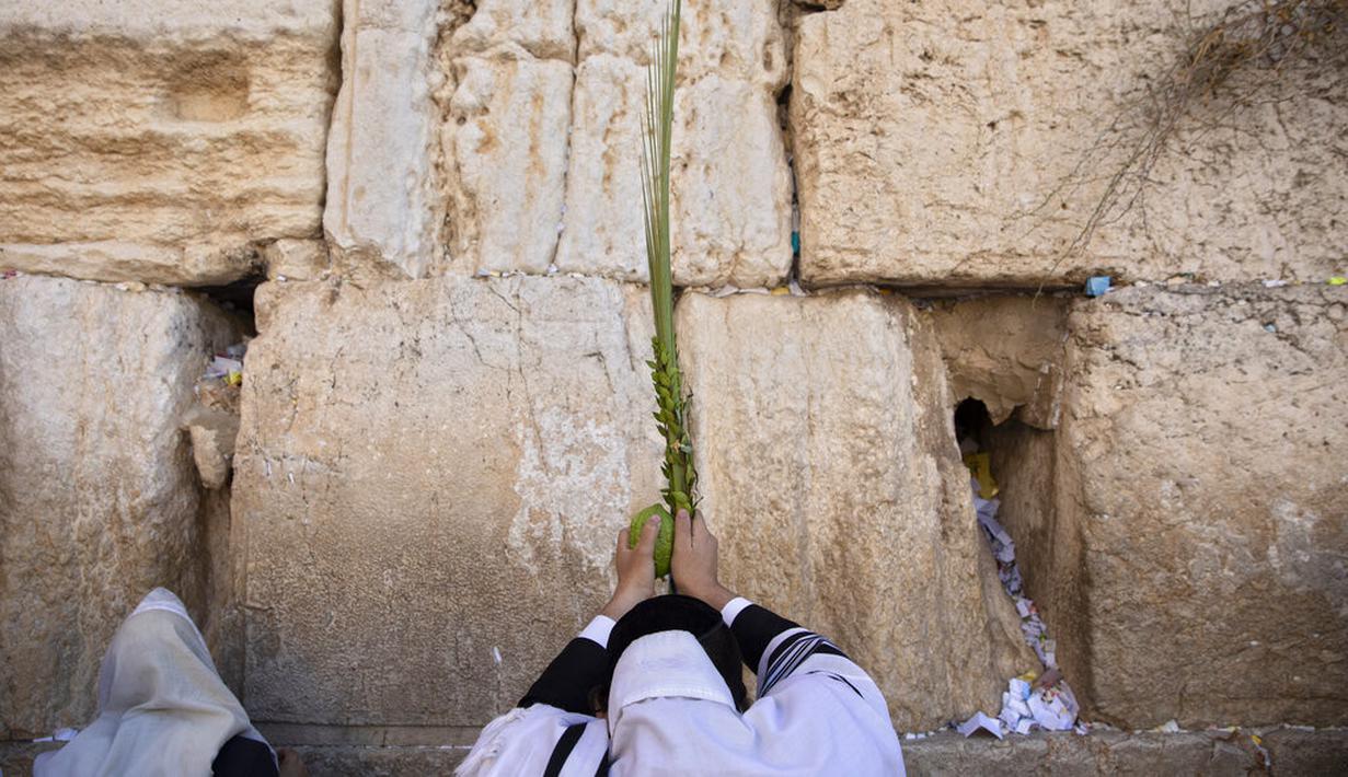Pria Yahudi Ultra-Ortodoks berdoa selama hari raya Yahudi Sukkot di Tembok Barat, situs paling suci di mana orang Yahudi dapat berdoa di Kota Tua Yerusalem, Rabu (22/9/2021).  (AP Photo/Sebastian Scheiner)