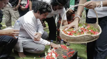Aktor Reza Rahadian menaburkan bunga di makam Benyamin Sueb di Karet Bivak, Jakarta, Jumat (26/1). Ziarah tersebut ditemani anak ketiga almarhum, H. Beni dan para fans, Benyamin Sueb Fans Club. (Liputan6.com/Faizal Fanani)