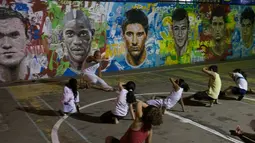 Anak-anak sedang berlatih seni bela diri khas Brasil Capoeira di dekat tembok lukisan wajah pemain top dunia, Brasil, Rabu (21/05/2014) (AFP PHOTO/Yasuyoshi CHIBA).