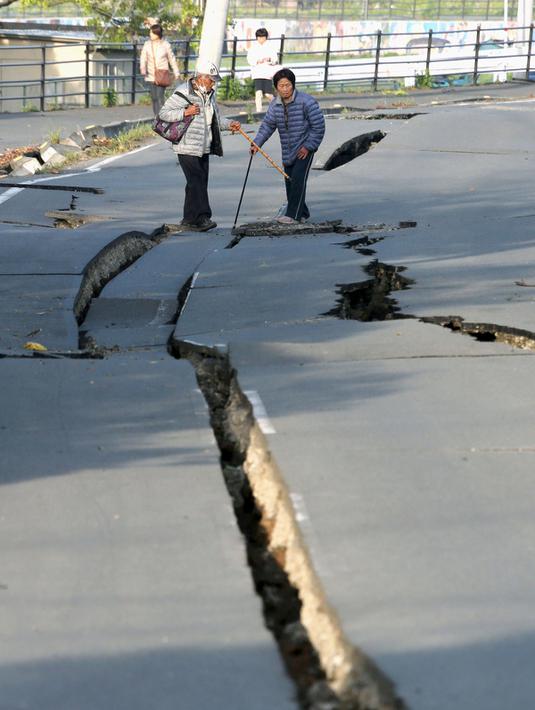 Penduduk setempat melihat jalan yang terbelah dua akibat gempa bumi yang menghantam kota Mashiki, Prefektur Kumamoto, Jepang selatan, Sabtu (16/4). Gempa berkekuatan 6,4 SR itu menewaskan sembilan orang dan 760 lainnya terluka. (REUTERS/Kyodo)