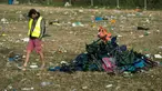 Seorang pria melewati kursi lipat dekat Pyramid Stage pada akhir Festival Glastonbury di arena Worthy Farm, Inggris, 26 Juni 2017. Penyelenggaraan festival musik terbesar di dunia itu menyisakan sampah yang berserakan di seluruh arena. (OLI SCARFF/AFP)