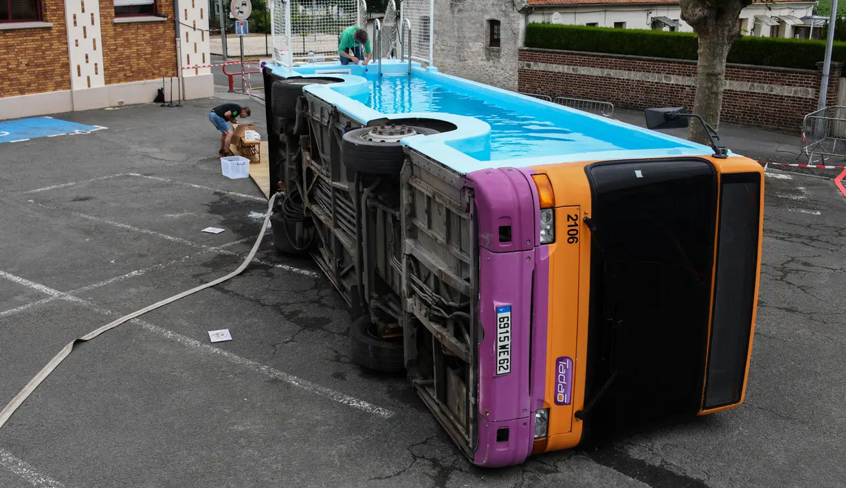 Seorang pria bekerja pada bus kota yang diubah menjadi kolam renang di Gosnay, Prancis Utara pada 15 Juli 2019. Karya seorang seniman Prancis, Benedetto Bufalino ini merupakan bus yang sudah dipensiunkan alias tak layak pakai untuk mengaspal di jalanan kota. (DENIS CHARLET / AFP)