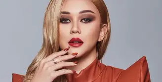 Dalam unggahan Instagram terbarunya, Aura Kasih tampil berbeda dengan rambut berwarna blonde atau pirang. Ia juga terlihat menggunakan leather clothes berwarna oranye. (Instagram/aurakasih).