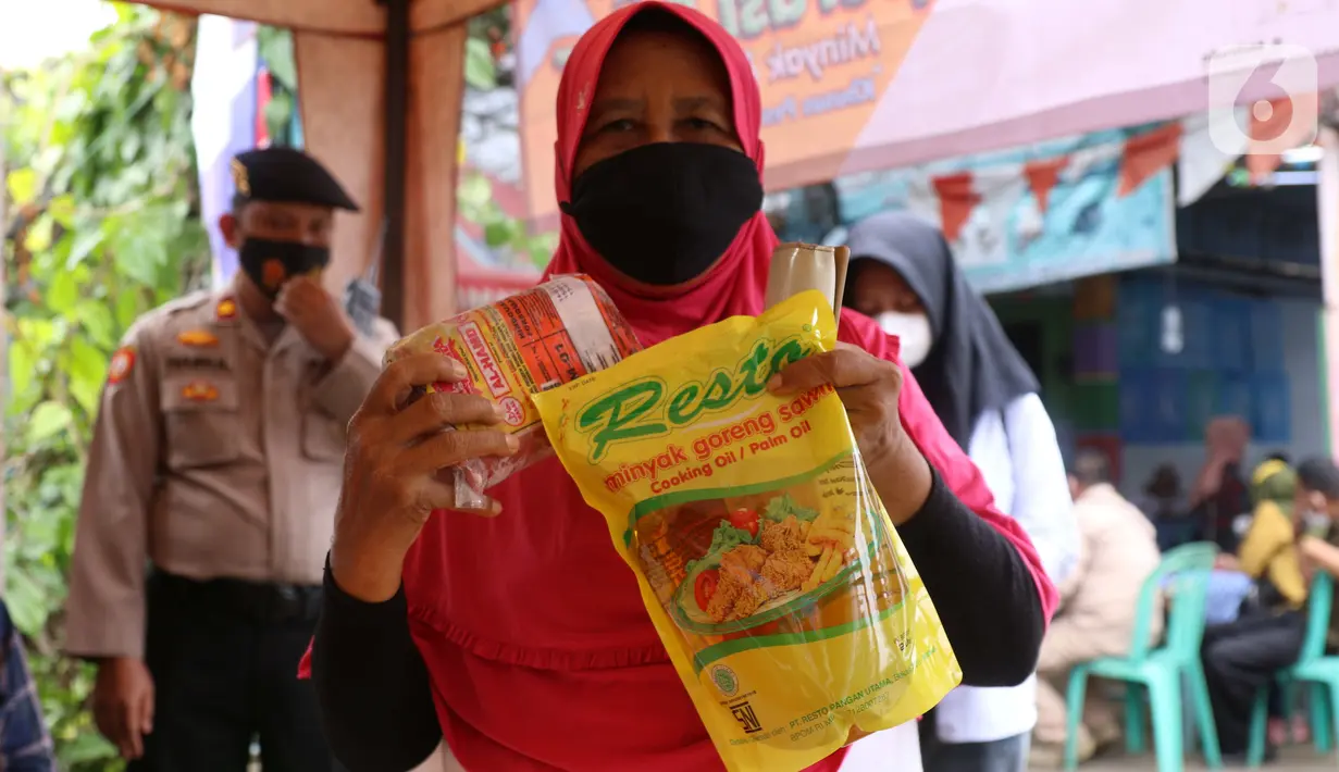 Warga menunjukkan minyak goreng dan daging kerbau seusai mengikuti vaksinasi covid-19 di kawasan Tanah Tinggi, Kota Tangerang, Jumat (4/3/2022). Pemkot Tangerang mengadakan operasi pasar minyak dan daging murah bagi warga yang melaksanakan vaksin covid-19 di lokasi. (Liputan6.com/Angga Yuniar)