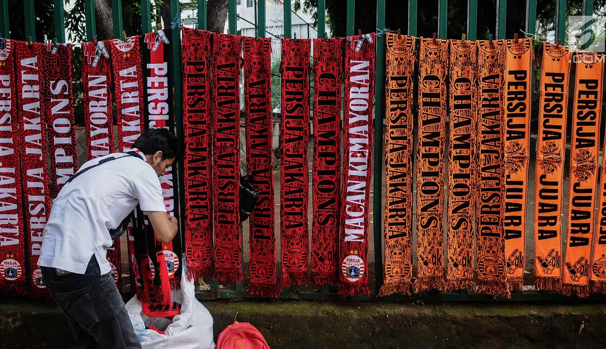 Pedagang merapikan syal Persija di kawasan Senayan, Jakarta, Minggu (9/12). Pedagang menjual aksesoris dan atribut Persija seperti baju, bendera, dan syal dengan kisaran harga Rp.50.000 - Rp. 100.000. (Liputan6.com/Faizal Fanani)