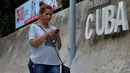 Seorang wanita menggunakan ponselnya untuk terhubung ke internet melalui WiFi di Havana, Rabu (5/12).Hampir setengah dari 11,2 juta penduduk Kuba memiliki ponsel, namun tidak semua akan mampu membeli paket internet ponsel. (YAMIL LAGE/AFP)