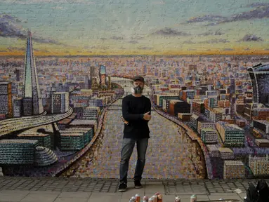 Seniman jalanan Australia James Cochran berpose di depan mural lanskap kota London buatannya di dinding Network Rail oleh Blackfriars Station, di London (5/10/2020). Ini adalah pertama kalinya Cochran melukis pemandangan kota sebagai karya seni jalanan di luar studionya. (AP Photo/Matt Dunham)