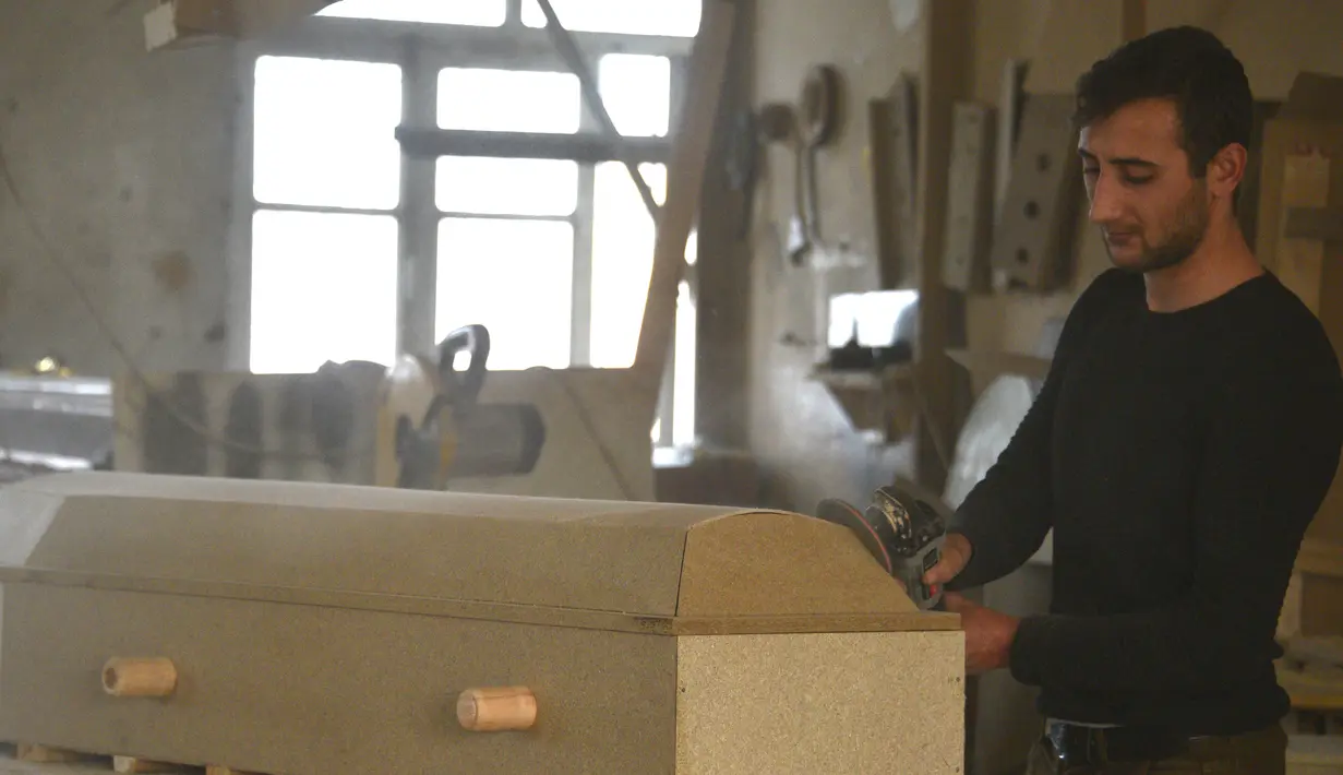 Seorang pria membuat peti mati di bengkel furnitur yang mengalihkan bisnisnya ke produksi peti mati di tengah konflik militer antara Armenia dan Azerbaijan atas wilayah yang memisahkan diri Nagorno-Karabakh, di ibu kota provinsi yang disengketakan, Stepanakert (4/11/2020). (AFP/Karen Minasyan)