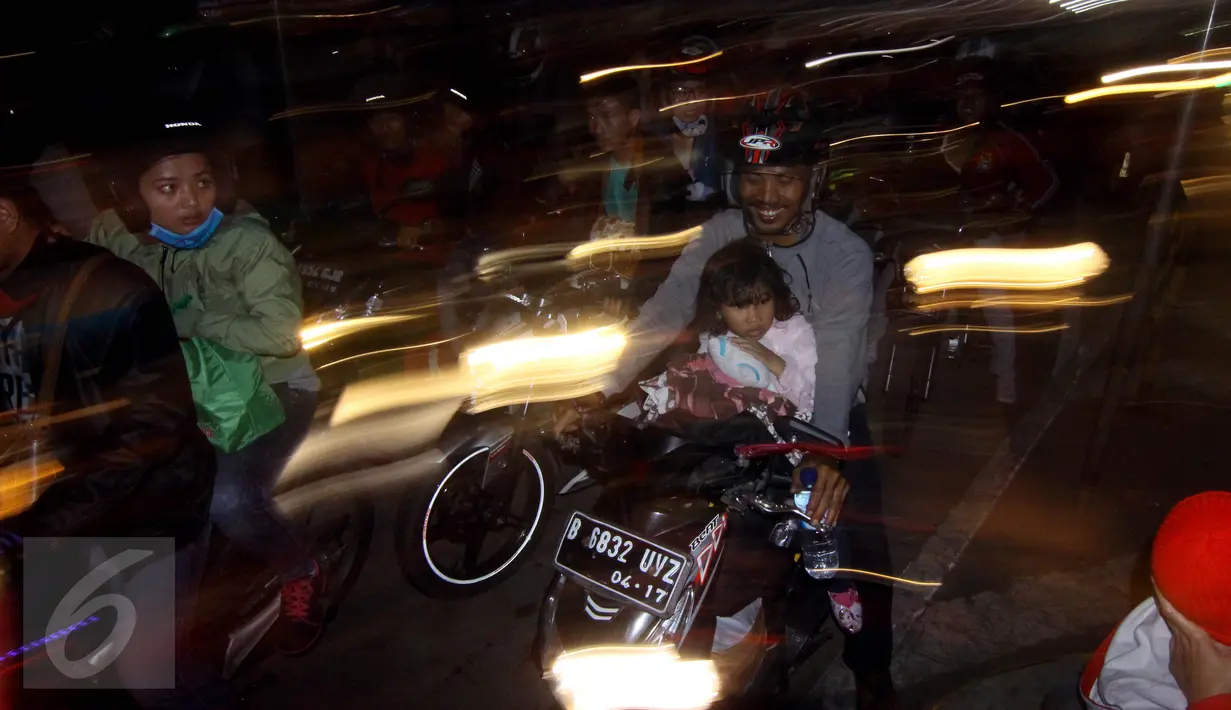 Seorang pemudik motor mengajak anaknya saat mengantre di Pelabuhan Merak, Banten, Rabu dinihari (15/7/2015). KPAI meminta pemudik yang menggunakan sepeda motor tidak membawa anak karena sangat membahayakan. (Liputan6.com/Johan Tallo)