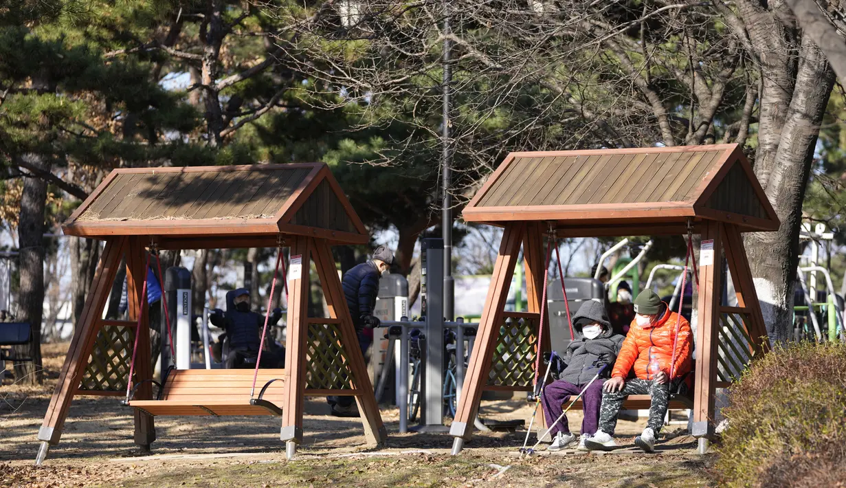 Pengunjung yang mengenakan masker sebagai tindakan pencegahan terhadap virus corona, beristirahat di sebuah taman di Goyang, Korea Selatan, Sabtu (4/12/2021). Korea Selatan kembali memecahkan rekor hariannya untuk infeksi dan kematian virus corona. (AP Photo/Lee Jin-man)