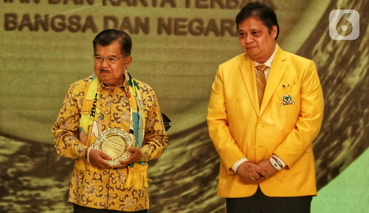 Wakil Presiden Indonesia ke-10 dan ke-12 Jusuf Kalla (kiri) membawa penghargaan didampingi Ketua Umum Partai Golkar Airlangga Hartarto (kanan) dalam peringatan HUT ke-55 Partai Golkar di Jakarta, Rabu (6/11/2019). (Liputan6.com/JohanTallo)