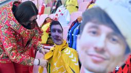 Seorang peremuan memasang maneken untuk menggantikan penonton saat pertandingan Liga Belarusia antara FC Dynamo-Brest dan FC Isloch di Brest, Minggu (12/4/2020). Kompetisi teratas Liga Belarusia ini menjadi satu-satunya liga di Eropa yang masih berjalan di tengah pandemi corona. (Sergei GAPON/AFP)