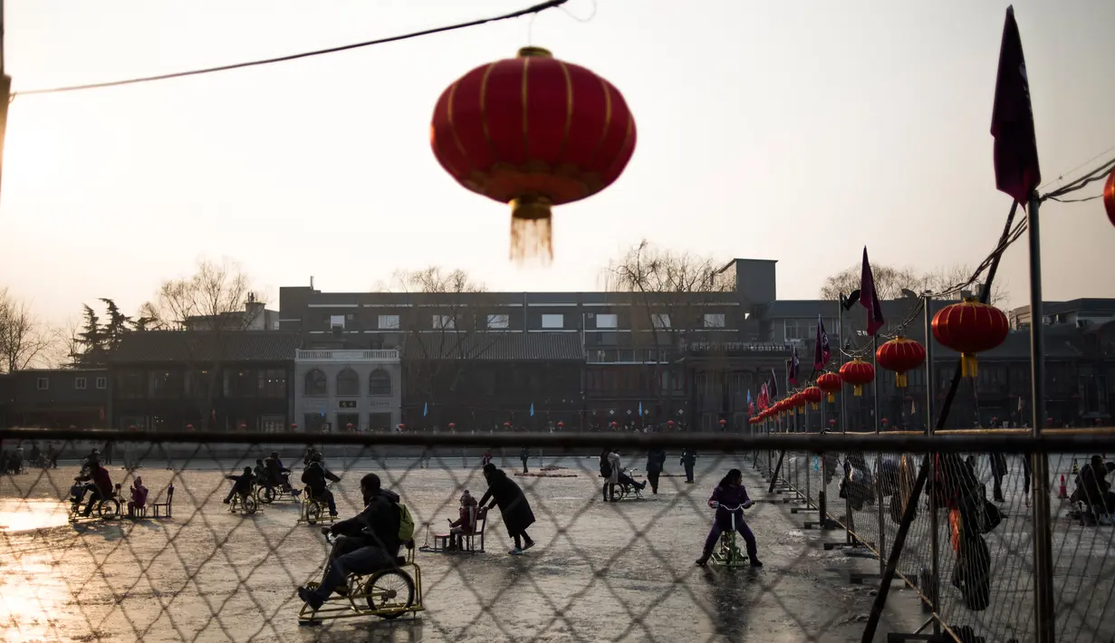 Sejumlah warga tampak menikmat bermain ice skating atau seluncur es di atas sungai yang telah membeku di Beijing, Jumat (1/1). Semenjak membeku, sungai di Beijing ini menjadi objek wisata es dadakan yang banyak diminati wisatawan.  (AFP/Fred Dufour) 