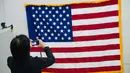 Pekerja memotret bendera Amerika Serikat di National Capital Flag Company, Alexandria Virginia, AS (10/1). Dalam acara tersebut Trump akan memberikan pidato resmi pertamanya sebagai presiden setelah membacakan sumpah. (AFP/Andrew Caballero Reynolds)