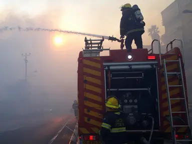 Petugas pemadam kebakaran menyemprotkan air ke arah hutan yang terbakar di kawasan Haifa, Israel, Kamis (24/11). Sekitar 50 persen dari kebakaran itu diduga disebabkan oleh aksi pembakaran yang disengaja. (REUTERS / Baz Ratner)