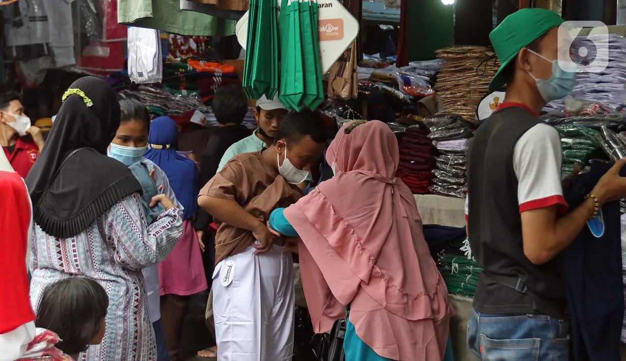 Pembeli mencoba seragam sekolah untuk anaknya di Pasar Mester, Jakarta , Minggu (29/8/2021). Menurut pedagang, penjualan seragam sekolah kembali meningkat hingga 30 persen jelang masuk sekolah tatap muka yang dilaksanakan kembali pada 30 Agustus 2021. (Liputan6.com/Herman Zakharia)