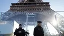 Polisi berpatroli di dekat Menara Eiffel yang dilindungi tembok kaca antipeluru di Paris,  Senin (30/12/2019). Pemerintah Prancis akan mengerahkan 100.000 petugas polisi untuk mengamankan ruang publik pada perayaan malam Tahun Baru di tengah aksi mogok yang sedang berlangsung. (AP/Christophe Ena)