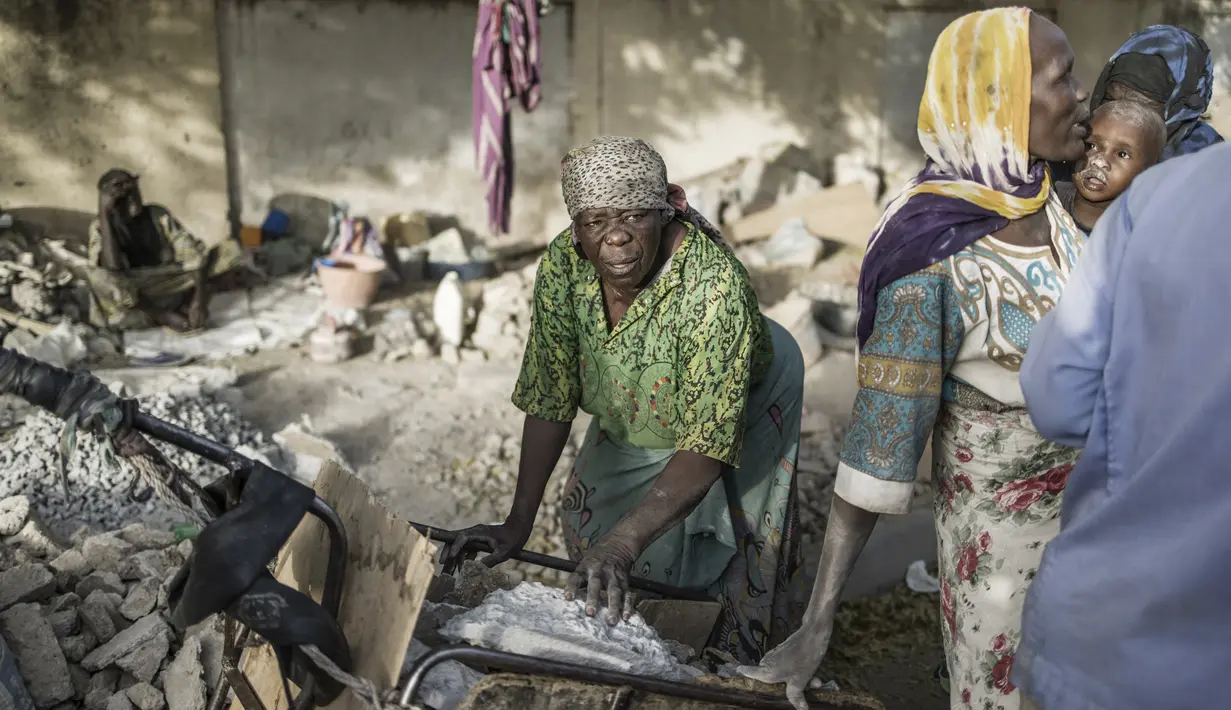 Habiba (ketiga kanan), penghancur kerikil berusia 50-60 tahun, dan Idjele (tengah), 38, memilih lempengan batu dari gerobak dekat Cite International des Affaires di N'Djamena, Chad, 12 April 2021. Dalam debu dan panas, wanita Chad menghancurkan kerikil untuk memenuhi kebutuhan. (MARCO LONGARI/AFP)