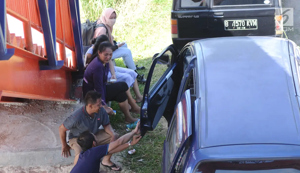 Pemudik beristirahat di pinggir jalan jelang gerbang keluar Tol Brebes Barat, Jawa Tengah, Sabtu (23/12). Untuk mengurangi kemacetan di pintu Tol Brebes Timur petugas mengalihkan arus lalu lintas keluar Tol Brebes Barat. (Liputan6.com/Helmi Fithriansyah)