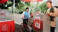 Petugas KPPS mengantar penyandang disabilitas memasukkan surat suara dalam simulasi pemungutan dan penghitungan suara Pilkada DKI Jakarta di Taman Menteng, Sabtu (28/1). Simulasi ini dilaksanakan oleh KPUD Jakarta Pusat. (Liputan6.com/Helmi Fithriansyah)