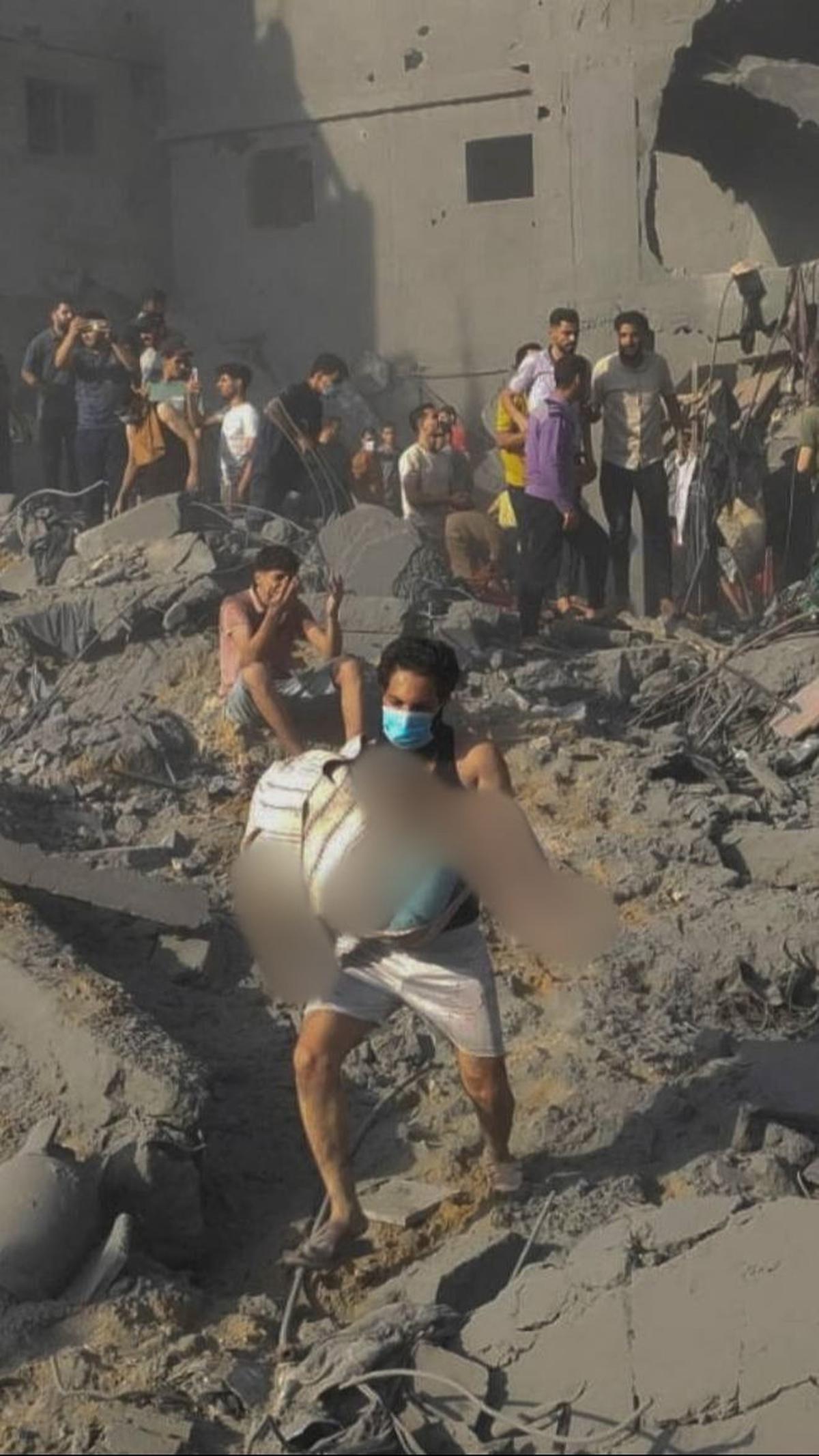 Seorang pria Palestina membawa jenazah kerabatnya di tengah proses evakuasi para korban usai serangan Isarel di kamp pengungsi Jabalia di Jalur Gaza utara.