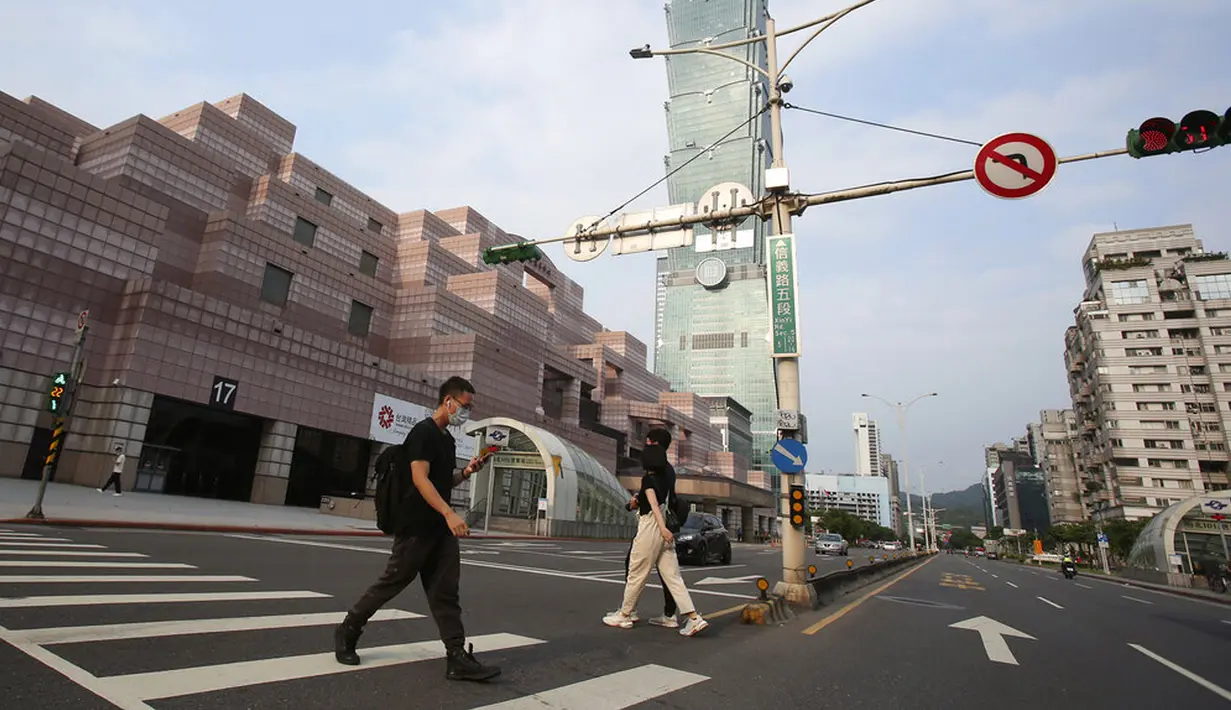 Warga memakai masker untuk melindungi diri penyebaran COVID-19 saat berjalan melewati Gedung Taipei 101 di Taipei, Taiwan, Sabtu (15/5/2021). Pandemi COVID-19 di Taiwan naik ke level tiga. (AP Photo/Chiang Ying-ying)