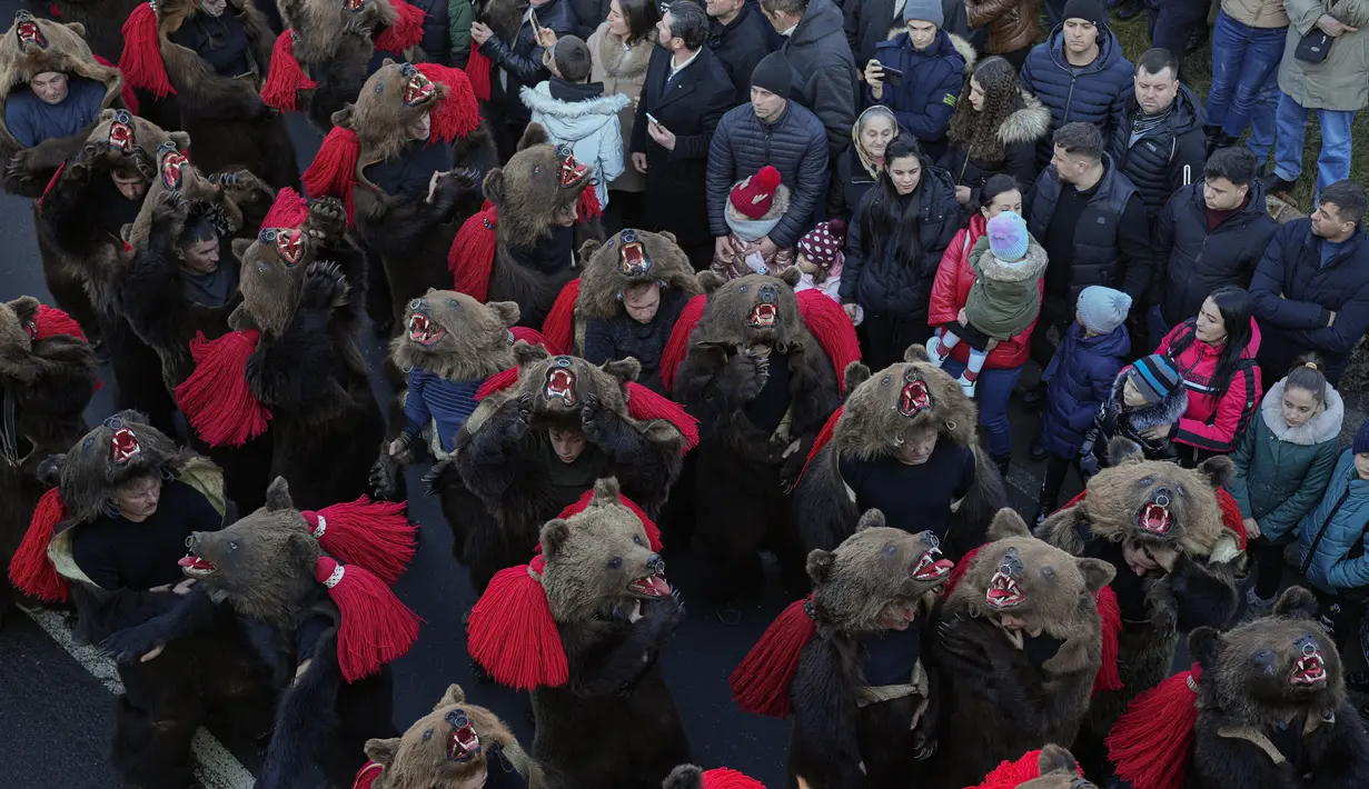 Orang-orang yang mengenakan kostum bulu beruang mengikuti parade di Comanesti, Romania, Jumat, 30 Desember 2022. Penduduk setempat khawatir tradisi itu akan hilang karena sejumlah besar pemuda Romania telah meninggalkan daerah itu untuk mencari kehidupan yang lebih baik di negara-negara Uni Eropa yang lebih kaya. (AP Photo/Vadim Ghirda)