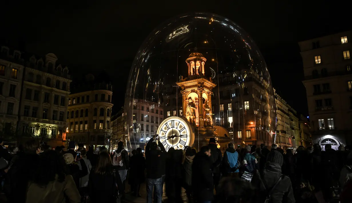 Pengunjung mengambil gambar sebuah bangunan yang diterangi cahaya dalam festival cahaya Fete des Lumieres di Lyon, Prancis, 7 Desember 2017. Musik, suara, dan video ikut mengiringi penampilan cahaya-cahaya itu. (AFP PHOTO / PHILIPPE DESMAZES)