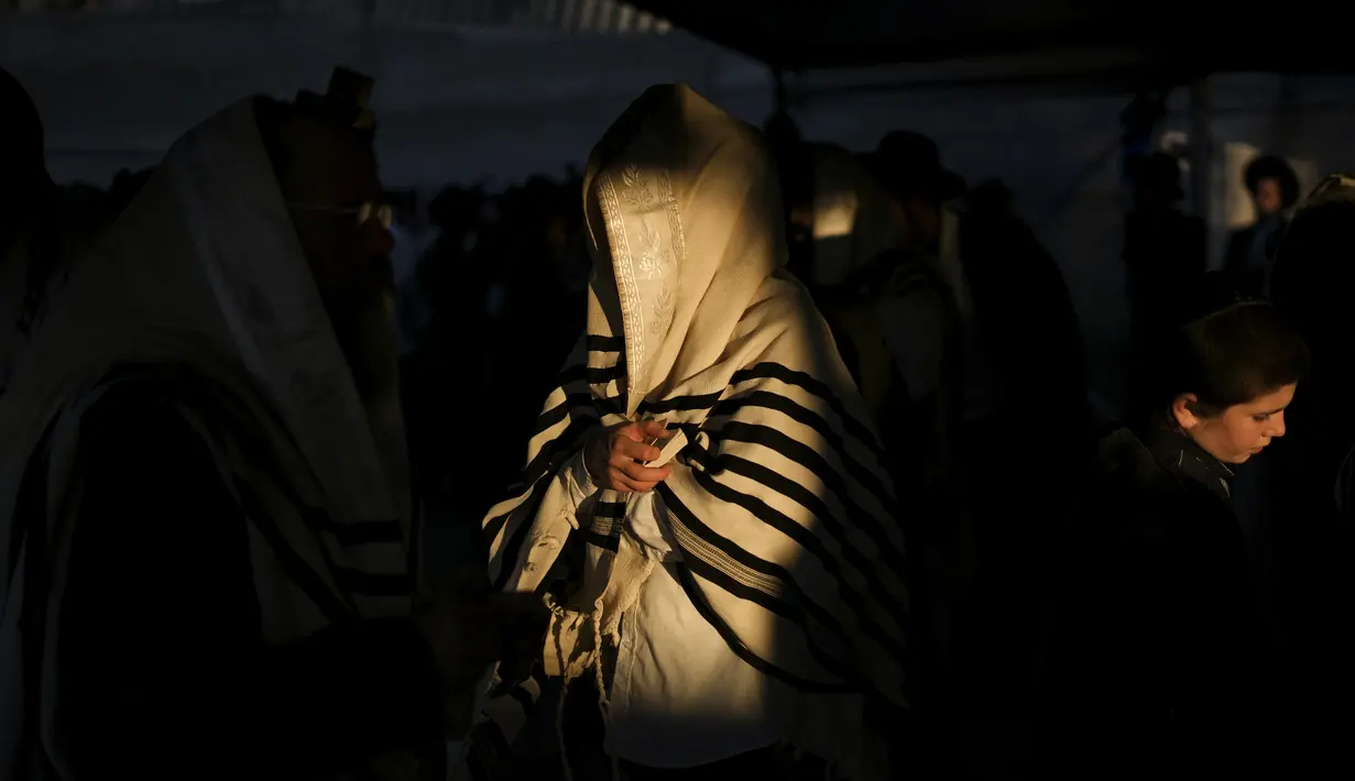 Orang-orang Yahudi Ultra Ortodoks yang ditutupi selendang berdoa saat perayaan liburan Lag BaOmer di situs makam tradisional Rabbi Shimon Bar Yochai di Gunung Meron, Israel, Kamis (19/5/2022). Orang Israel menyalakan api unggun selama perayaan Lag BaOmer untuk memperingati berakhirnya wabah yang dikatakan telah memusnahkan orang Yahudi di zaman Romawi. (AP Photo/Ariel Schalit)